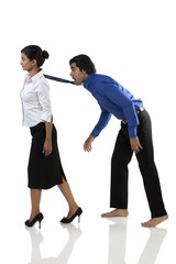 Businesswoman pulling a businessman's tie 