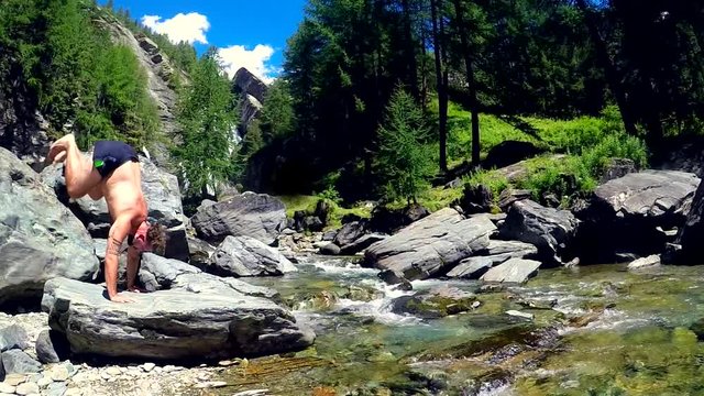 Uomo che fa la verticale in mezzo allanatura e un fiume