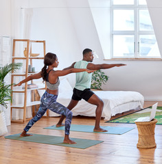 African couple exercising doing yoga together at home