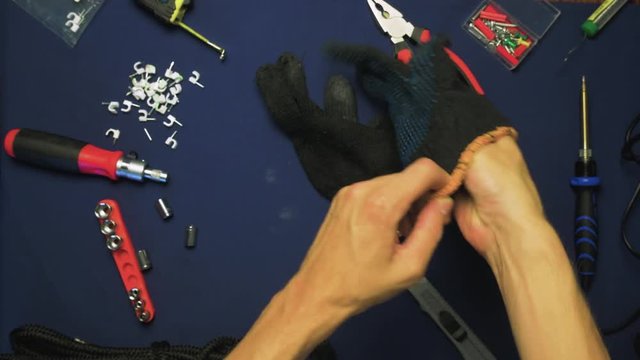 Top View Man Put On Black Gloves On Hands, On The Table Are Visible Tools