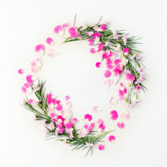 Flat lay frame wreath with carnation flowers and rose petals and green leaves on white. Top view holiday concept.