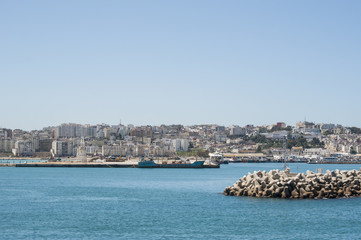 Marocco: una nave nel porto e lo skyline di Tangeri, città marocchina sulla costa del Maghreb all'entrata occidentale dello stretto di Gibilterra, dove il Mar Mediterraneo incontra l'Oceano Atlantico