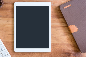 White tablet and blank notebook on wooden table