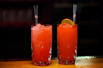 Two red cocktail drinks on black background on green table. Space in background for copy, text, your words