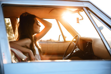 Side view of a woman sitting inside a retro car