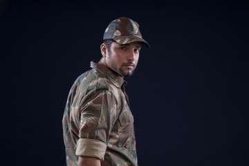 Portrait of young soldier standing over black background 
