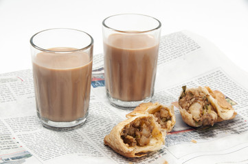 Indian chai with samosas on newspaper isolated over white background 