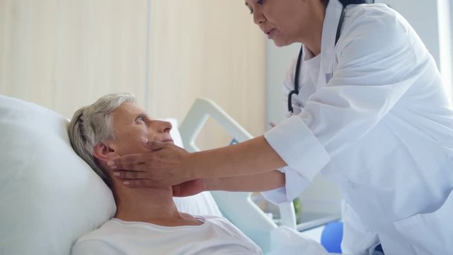 Professional female doctor examing a senior sick man