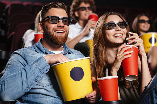 Happy friends sitting in cinema watch film