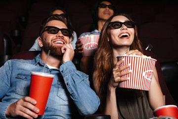 Happy friends sitting in cinema watch film - obrazy, fototapety, plakaty