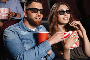 Fototapeta premium Concentrated friends loving couple sitting in cinema