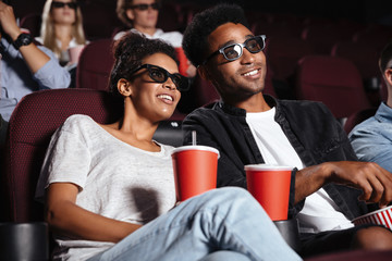 Happy friends sitting in cinema watch film eating popcorn