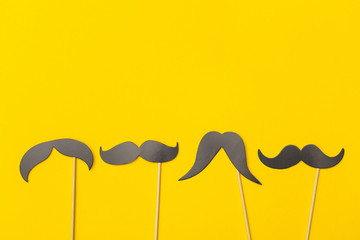 Moustache on a stick on a bright yellow background