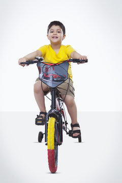 Full length portrait of boy riding bicycle over white background