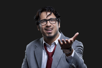 Frustrated young businessman gesturing over black background