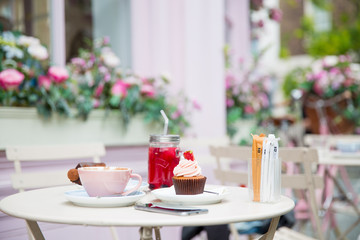 Photography of beautiful cake and cup of tea and cocktail on a table in front of restaurant