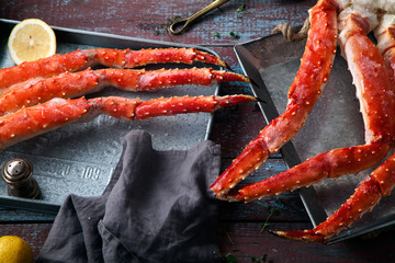 Fresh crab claws on metallic tray vintage wooden background with copper plates and lemon slices. Composition with copy space