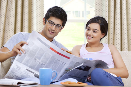 Young couple reading newspaper together 