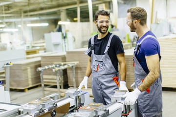 Young workers working in furniture factory - obrazy, fototapety, plakaty