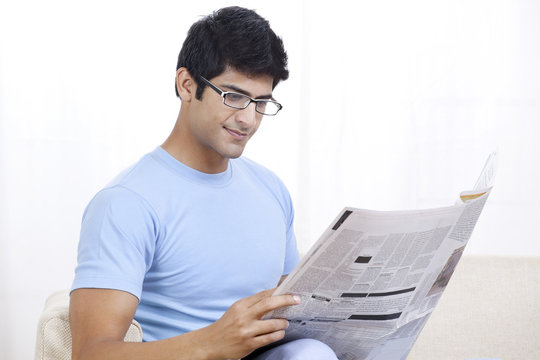 Young Indian man reading global news at home 