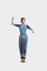 Full length of beautiful dancer performing Bharatanatyam against white background