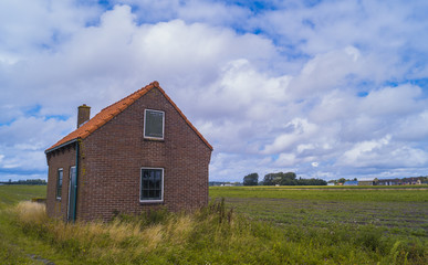 Fototapeta na wymiar a small shed in a meadow field with a blue sky and clouds in the background. The Netherlands.