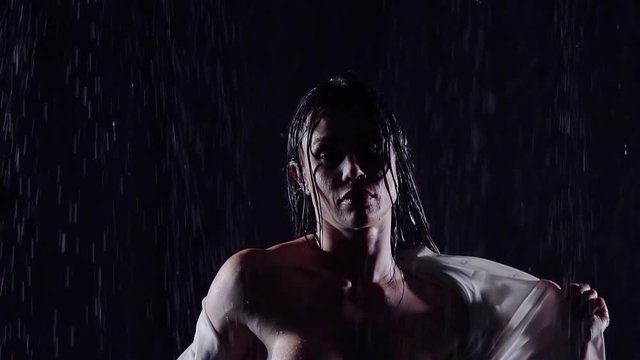wet night in the rain girl with big cheekbones removes wet white shirt revealing his athletic, muscular female body