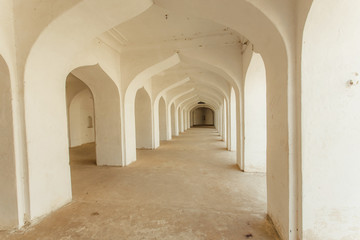 Fototapeta na wymiar White arches in indian house with long corridor inside. Old building in India.
