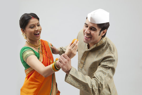 Maharashtrian Man Trying To Eat A Laddoo From A Woman's Hand