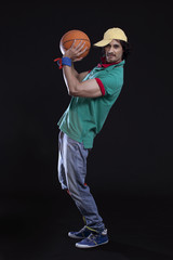 Full length of funky young man about to throw basketball against black background 