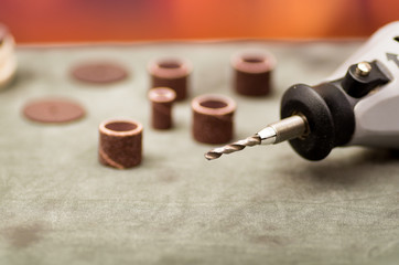 Close up of selective focus of a gray drill with drilling accessories on gray table in a blurred...