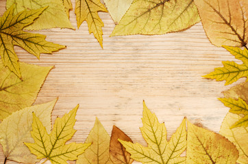 Naklejka na ściany i meble Frame of yellow autumn leaves on a wooden background. Autumn greeting card with leaves. Copy space
