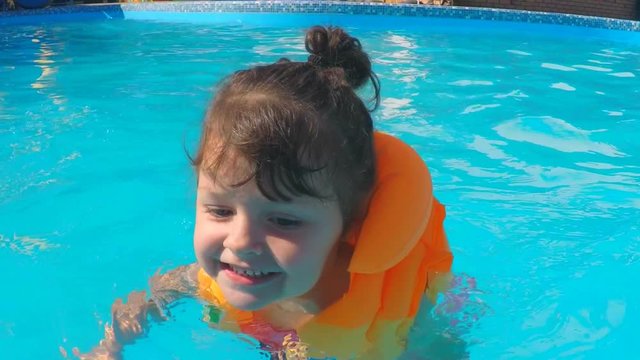 The child is swimming in the pool. Emotions of a little girl in the pool.