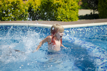 Blond little girl in the swimming pool. Happy smiling girl