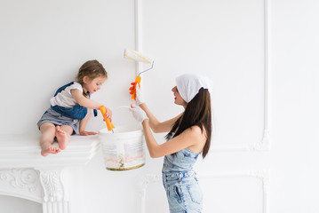 The young happy mother stands near her daughter and they keep platens in hands and do repair at home