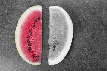 Two sweet watermelon slices on black and white background, one slice is colored