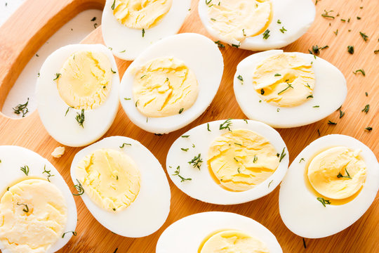Cut boiled eggs with dill on a cutting board close-up