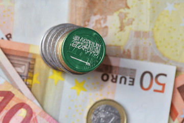 euro coin with national flag of saudi arabia on the euro money banknotes background.