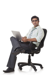 Portrait of male executive on office chair using laptop 