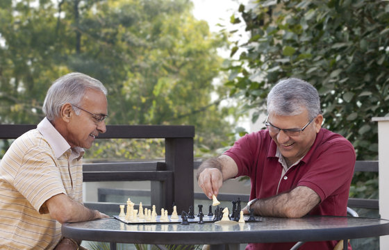 Happy senior men playing chess together 