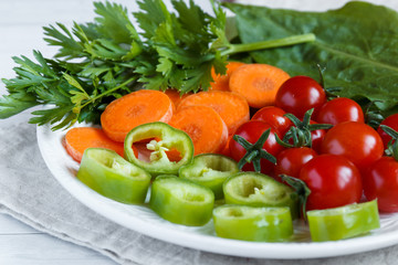 Fresh vegetables, cherry Tomato, green pepper carrot greens mugs on wooden background.