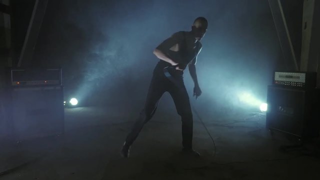 A brutal singer of a rock band sings into a microphone. Music video punk, rock, hardcore, heavy metal band. Shot on steadicam