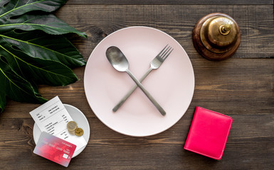 Ask for the bill at restaurant. Service bell near plate whith crossed spoon and fork on wooden table top view