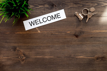 Check in at the hotel. Word welcome near room keys on dark wooden table background top view copyspace