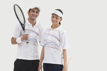 Portrait of happy male and female tennis players standing together isolated over white background