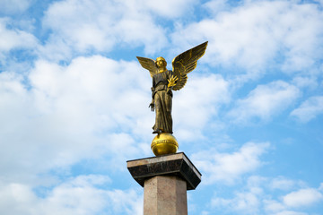 Statue of an angel on a high pedestal against the sky.