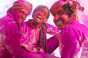 Young Indian Men sitting on floor, covered in colored powder during holi color festival