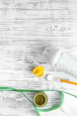 Preparing to feed baby. Puree, spoon, nipple, bottle and bib on light wooden table background top view copyspace