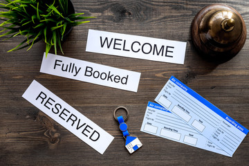 Preparing to trip. Book hotel and tickets. Tickets near service bell, bank card on dark wooden...