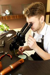 A jeweler carefully examines the stone to create a ring through a microscope